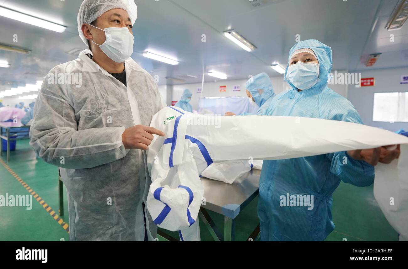 Wuhan, Chinas Provinz Hubei. Januar 2020. Ein Mitarbeiter stellt die Schutzanzüge vor, die in der Werkstatt eines Unternehmens in Wuhan, der zentralchinesischen Provinz Hubei, am 28. Januar 2020 hergestellt wurden. Um den Ausbruch einer Lungenentzündung zu bekämpfen, die durch neuartige Coronavirus verursacht wurde, eilten Arbeiter der örtlichen medizinischen Materialunternehmen in der Provinz Hubei zurück zur Arbeit, um Schutzmasken, Kleidung und andere Schutzausrüstungen für die Versorgung zu fertigen. Credit: Cai Yang/Xinhua/Alamy Live News Stockfoto