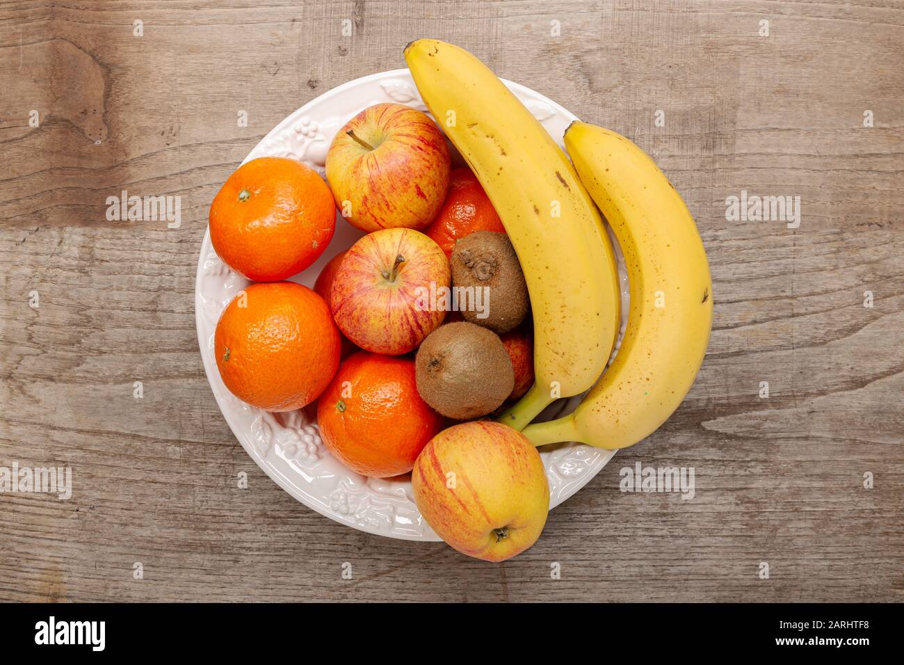 Draufsicht auf Obst in einer Schüssel auf Holztisch. Gesundes Lebensmittelkonzept Stockfoto