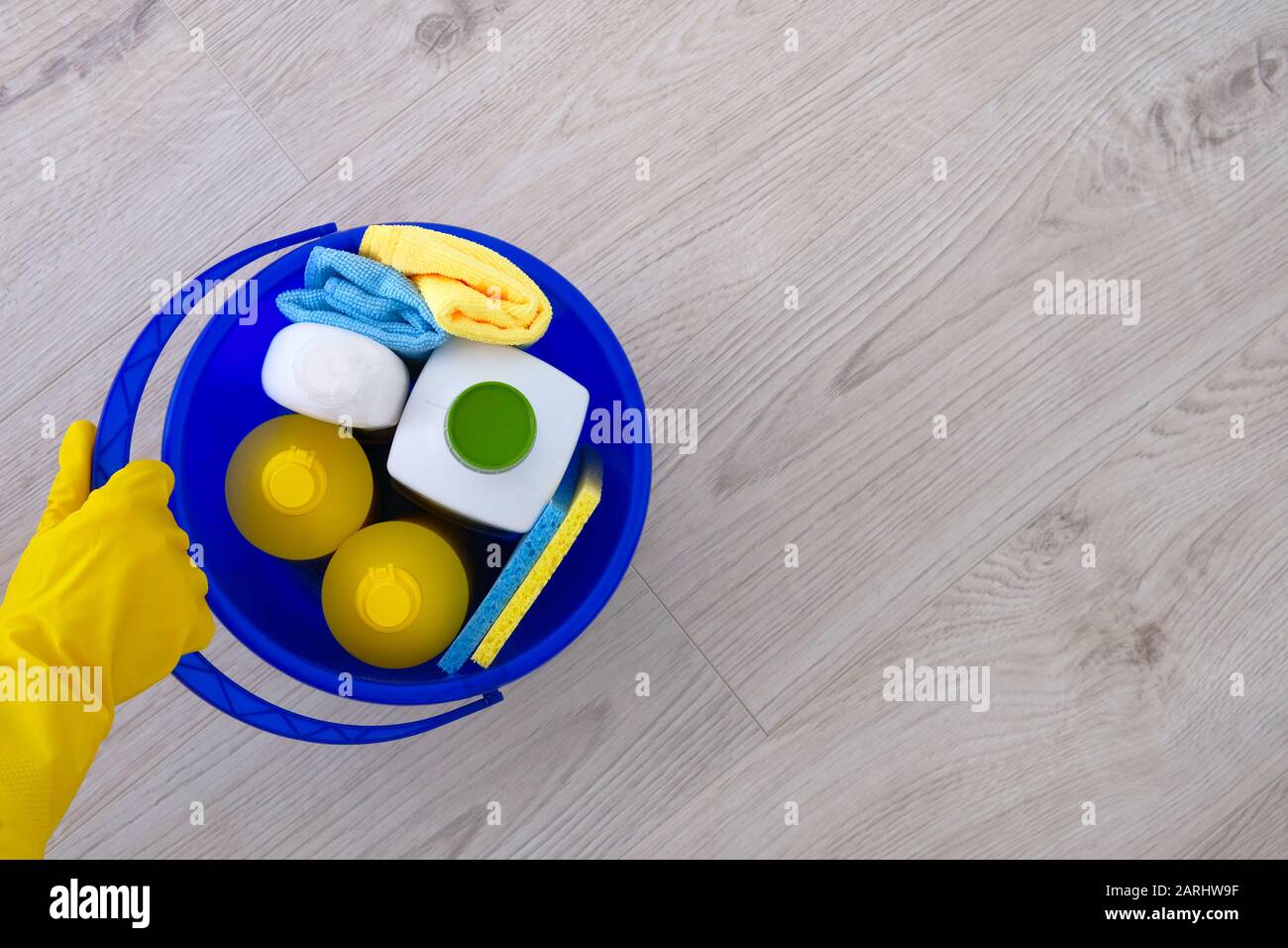 Waschmittel in Kunststoffflaschen, Schwämmen, Bürste in blauem Haushaltsbecher. Hand in gelbem Gummihandschuh. Сleaning Zubehör. Flaches Lay. Kopierbereich. Stockfoto Waschmittel in Kunststoffflaschen, Schwämmen, Bürste in blauem Haushaltsbecher. Hand in gelbem Gummihandschuh. Сleaning Zubehör. Flaches Lay. Kopierbereich. Stockfoto