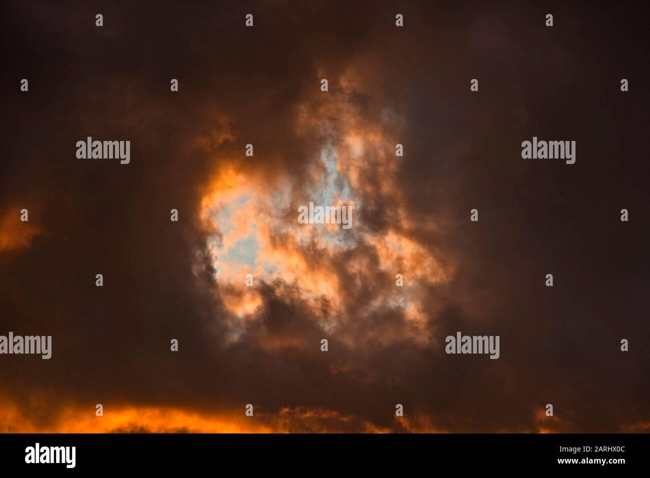 Sonnenuntergang durch abfliegende Sturmwolken, die einen hoffnungsvollen blauen Himmel über dem Kopf zeigen Stockfoto