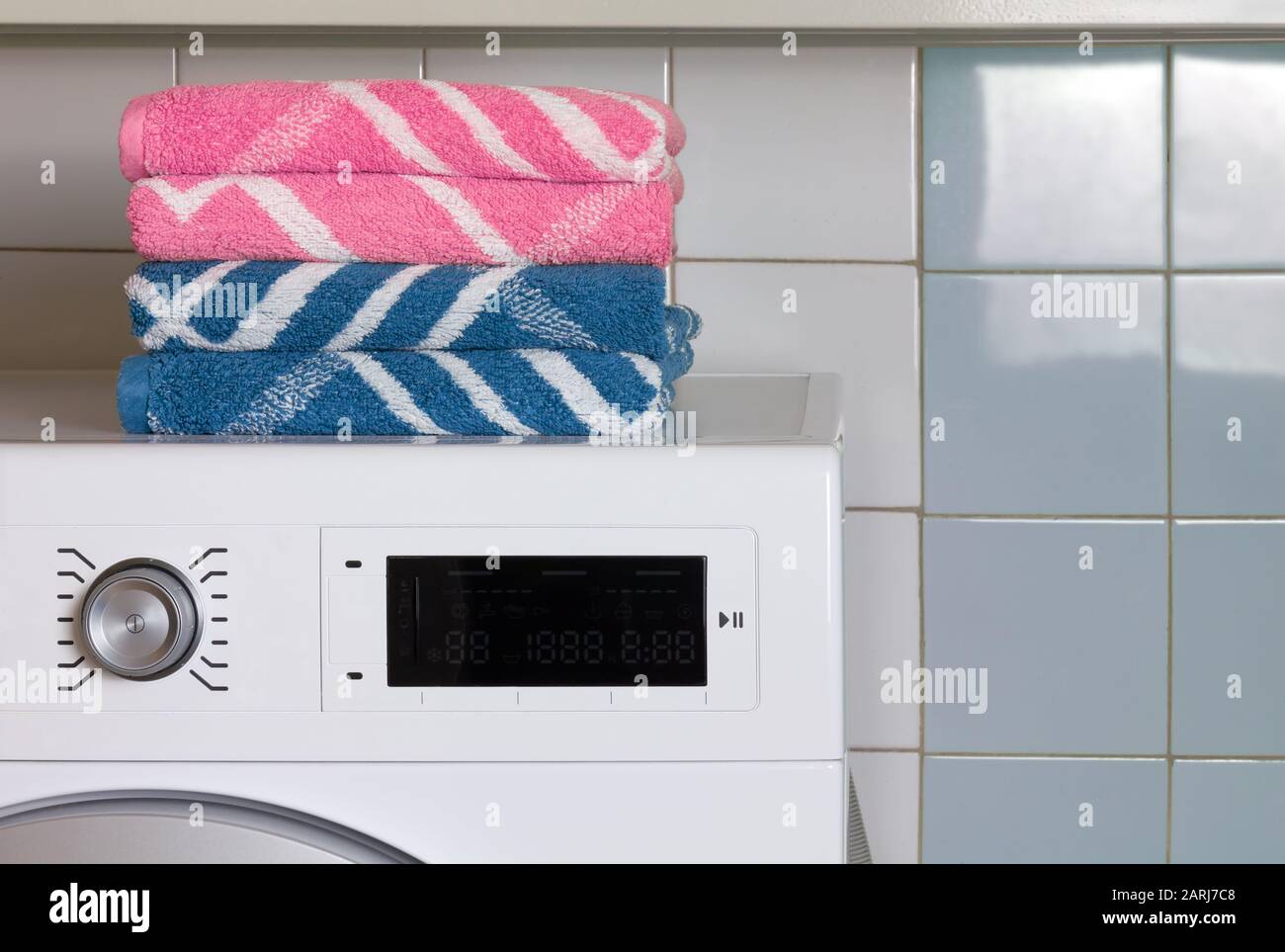 Zwei blaue Handtücher und zwei rosafarbene Handtücher auf der Oberseite  einer Waschmaschine in einer Waschküche Stockfotografie - Alamy