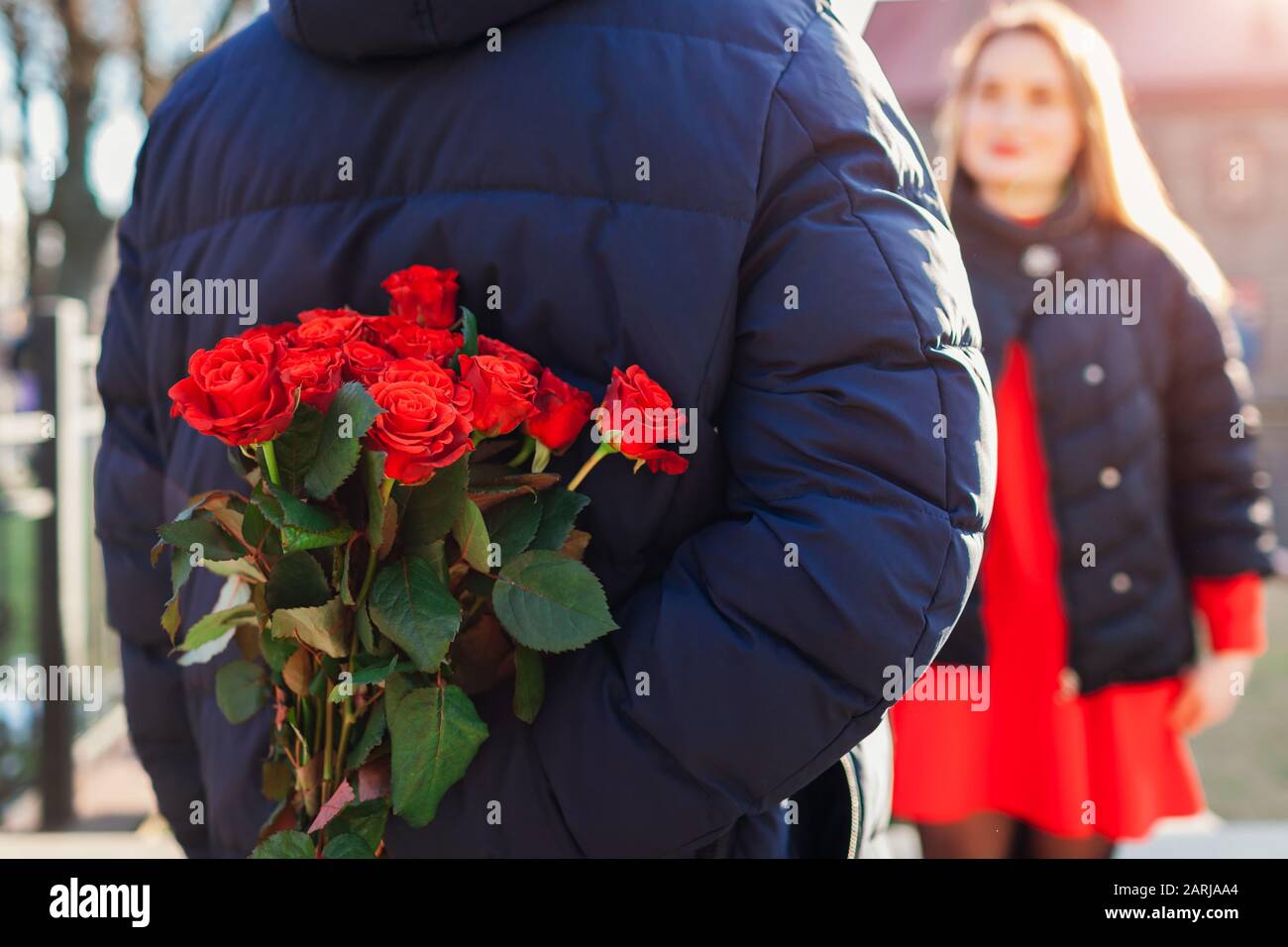 Valentinstag Rosen. Mann versteckt Blumenstrauß von Freundin hinter seinem Rücken an seinem Tag im Freien. Damen Day Stockfoto