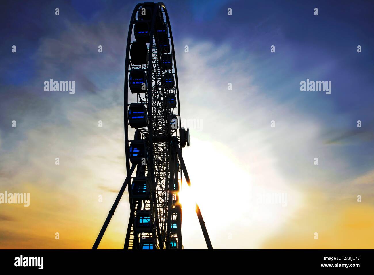 Detail eines Riesenrads gegen den dramatischen Himmel bei Sonnenuntergang. Stockfoto