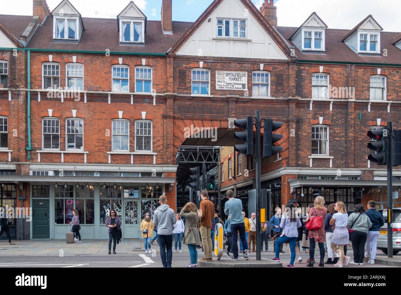 Old Spitalfields Market, Commercial St, Spitalfields, London, Großbritannien. Menschen, die auf die Querung der Straße an einem Fußgängerübergang warten. Stockfoto