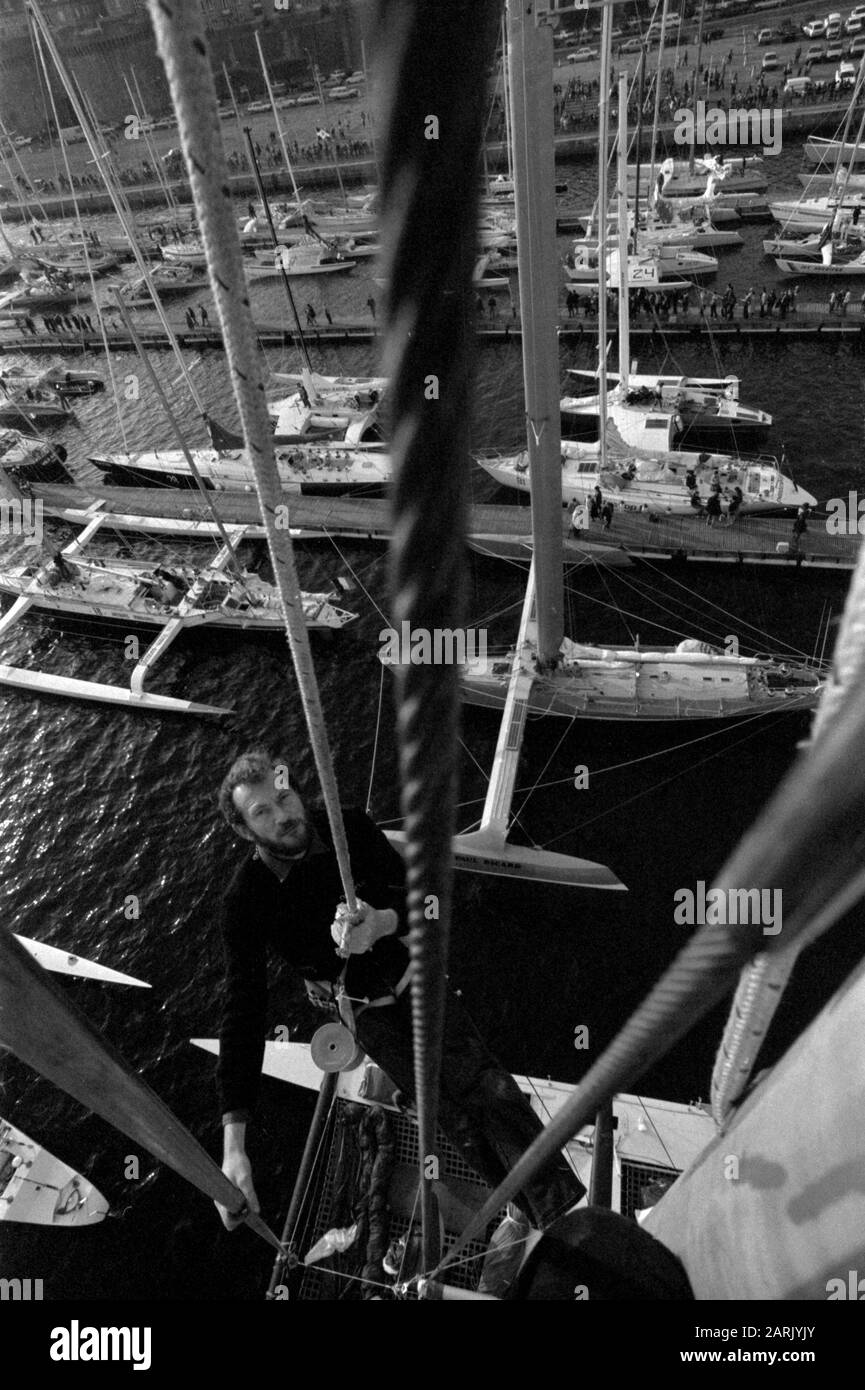 AJAXNETPHOTO.1982. SAINT-MALO, FRANKREICH. - ROUTE DU RHUM RACE - ROBIN KNOX-JOHNSTON (GBR), EIN EINSTIEG IN DAS EINHANDRENNEN, SKALIERT DEN MAST SEINES NEUEN CATAMRAN OLYMPUS 3 MIT ANDEREN KONKURRENTEN IN BASSIN VAUBIN. FOTO: JONATHAN EASTLAND/AJAX REF:821007 13A016 Stockfoto