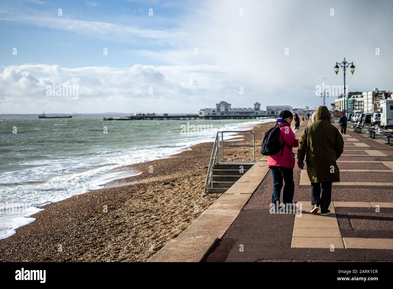 Ein Paar Frauen mittleren Alters, die im Winter am Strand in Southsea, Hampshire spazieren gehen Stockfoto