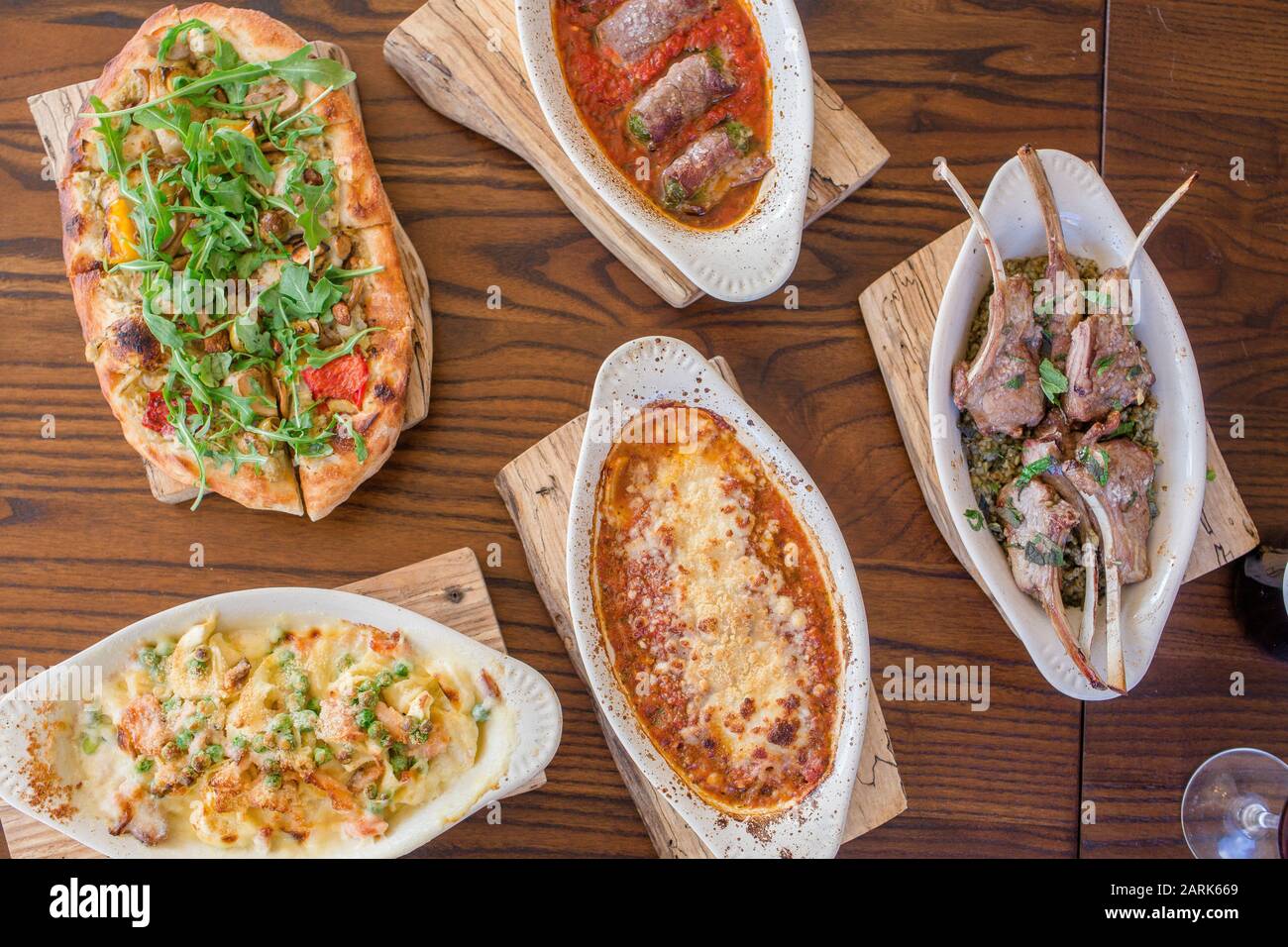 Auf einem Holztisch wird eine Auswahl italienischer Gerichte serviert Stockfoto