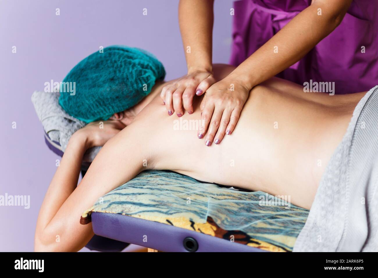 Professionelle Massagetherapeutin knetet zurück von Klient durch ihre Hände Stockfoto
