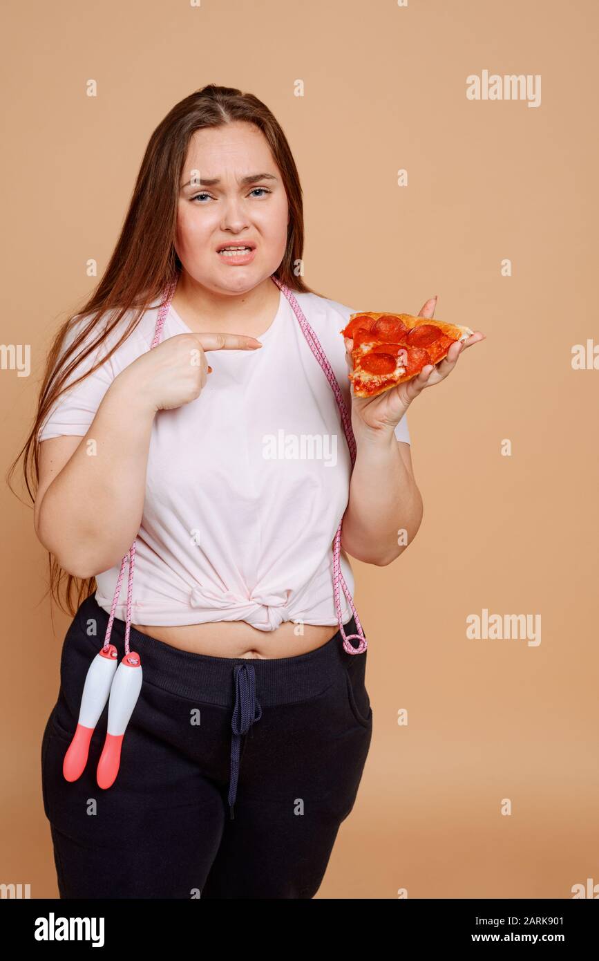 Übergewichtige Frau will Pizza, aber sie ist nicht erlaubt Stockfoto