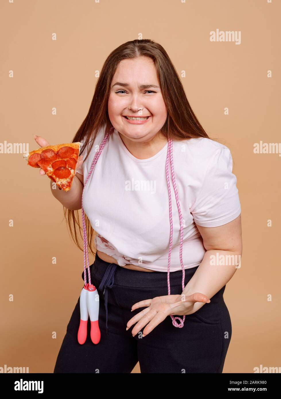 Schluchzende übergewichtige Mädchen versuchen, sich zu überwinden und keine Pizza zu essen Stockfoto
