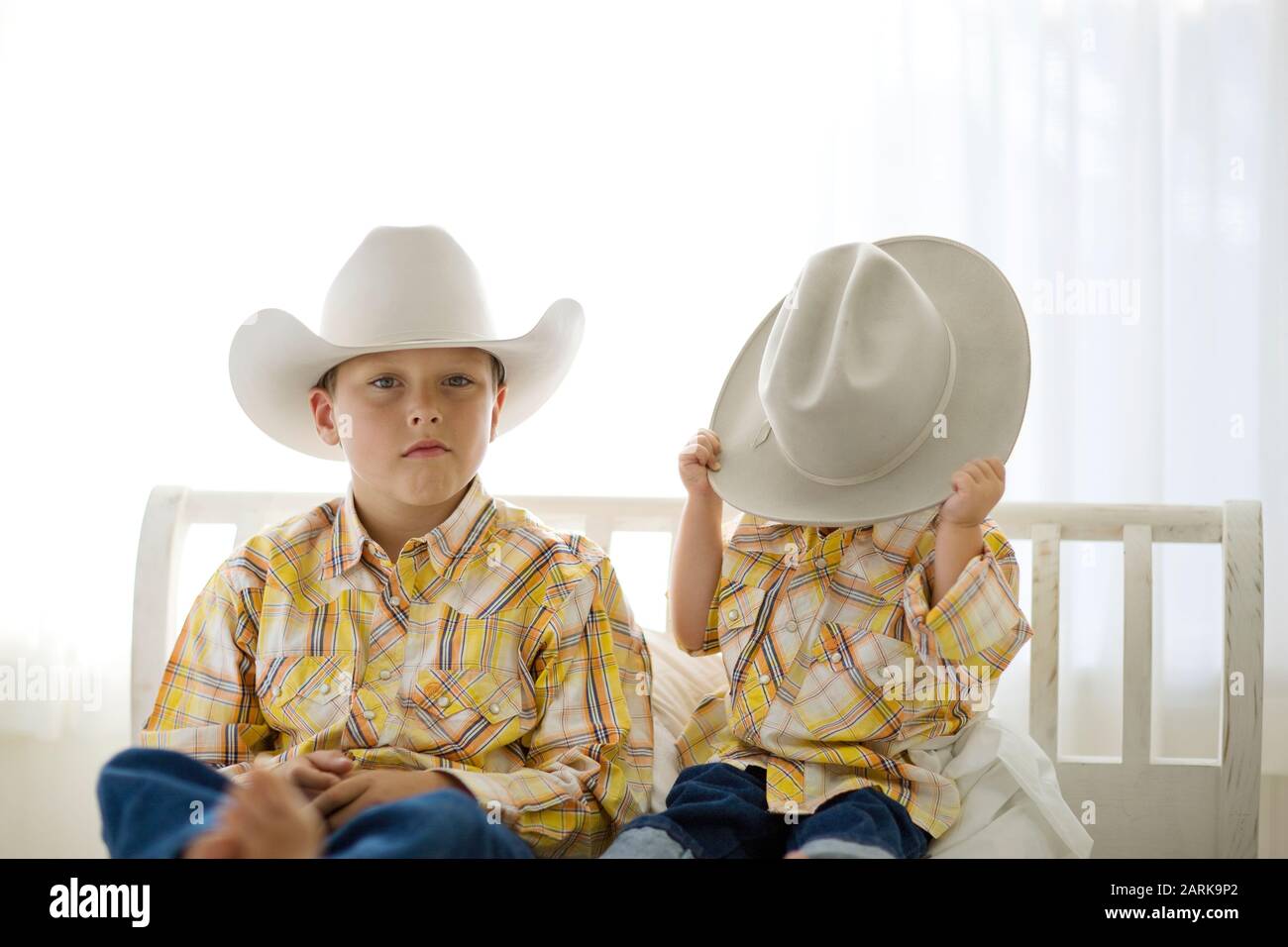 Porträt eines Jungen tragen einen Cowboyhut sitzen neben seinen jüngeren Bruder. Stockfoto