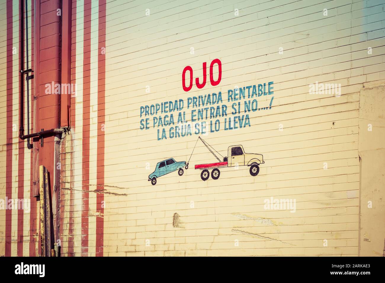 Die spanische Sprache, die auf die alte Mauer aus Backstein mit kindlicher Zeichnung und Warnung zum Parken auf Privatgrundstück oder Auto eingekesselt ist, wird von Tow TR geschleppt Stockfoto