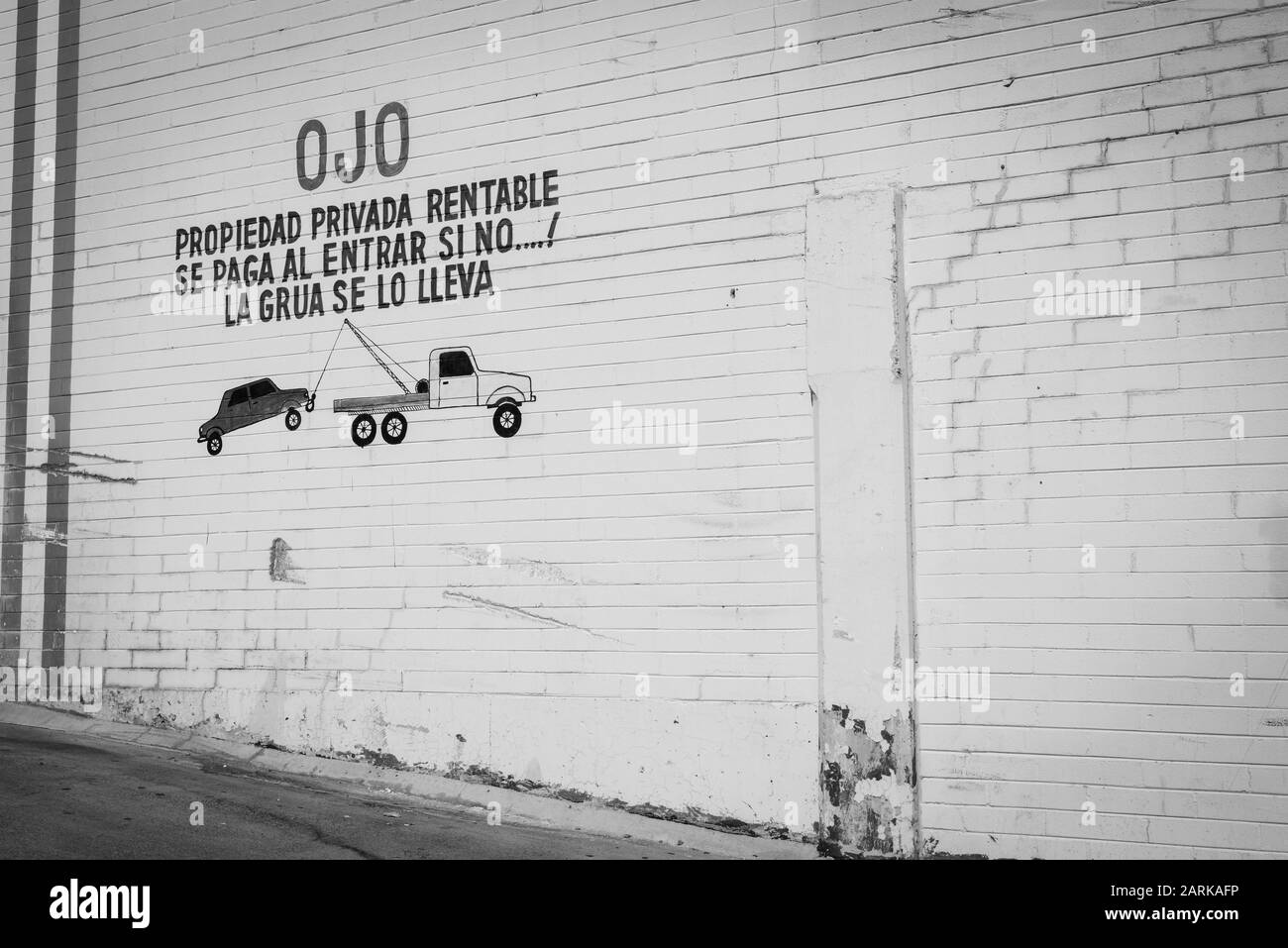 Die spanische Sprache, die auf die alte Mauer aus Backstein mit kindlicher Zeichnung und Warnung zum Parken auf Privatgrundstück oder Auto eingekesselt ist, wird von Tow TR geschleppt Stockfoto