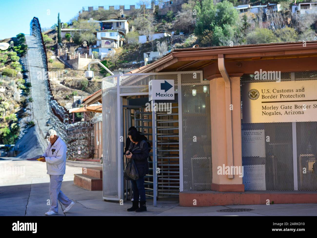 Menschen, die die US-amerikanische/mexikanische Grenze zu Fuß am Grenzpunkt Morley Gate von der Einreise in die USA mit Grenzzaun und mexikanischen Häusern im Hintergrund überqueren Stockfoto