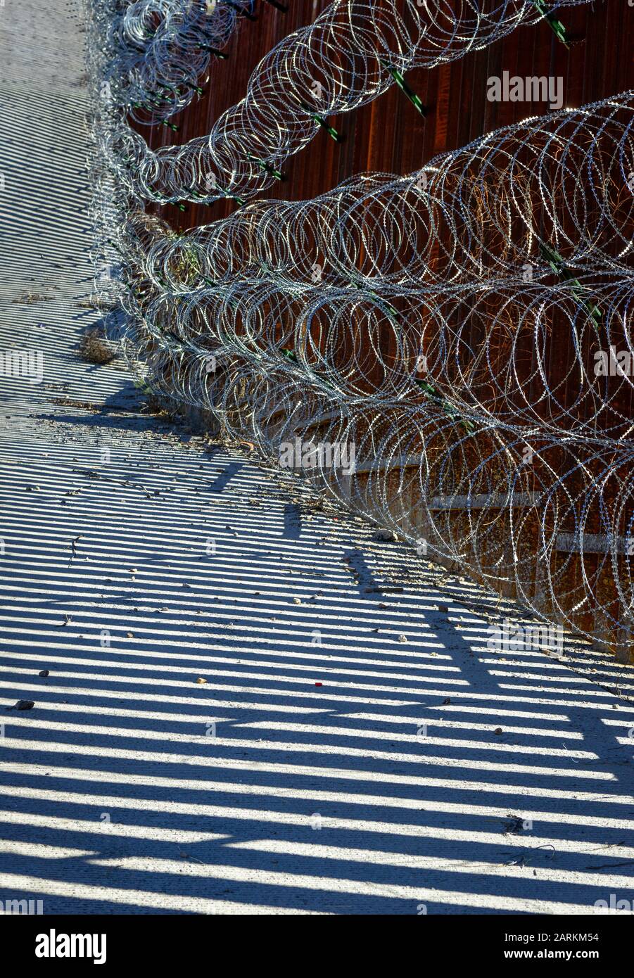 Abstrakte Ansicht des internationalen Grenzzauns USA/Mexiko mit Rasierdraht mit dramatischem Licht und Schatten in Nogales, AZ, USA, Stockfoto