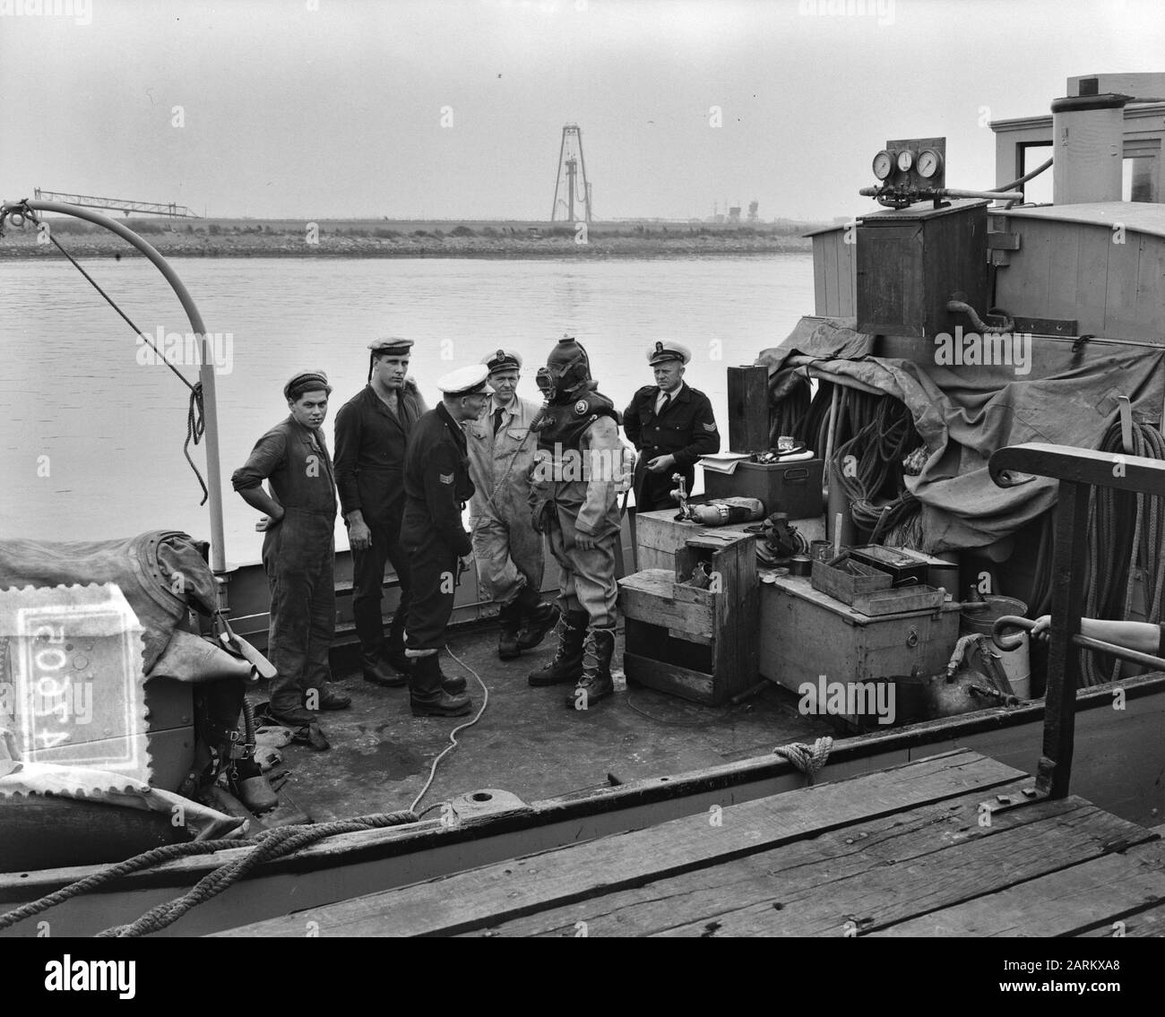 In den Helder wird von belgischen Marineangehörigen zur Ausbildung zum Taucher praktiziert. Einer der Belgier im Tauchanzug - ein so genannter Verfolgungsanzug, der kürzlich von der niederländischen Marine in Gebrauch war - ist bereit, vom Tauchschulungsschiff herabzusteigen. Völlig richtig einer der anderen Belgier, der in der Ausbildung zum Taucher ist Datum: 12. september 1951 Standort: Den Helder, Noord-Holland Schlüsselwörter: Taucher, Marine, Ausbildungseinrichtung Name: Marine Stockfoto