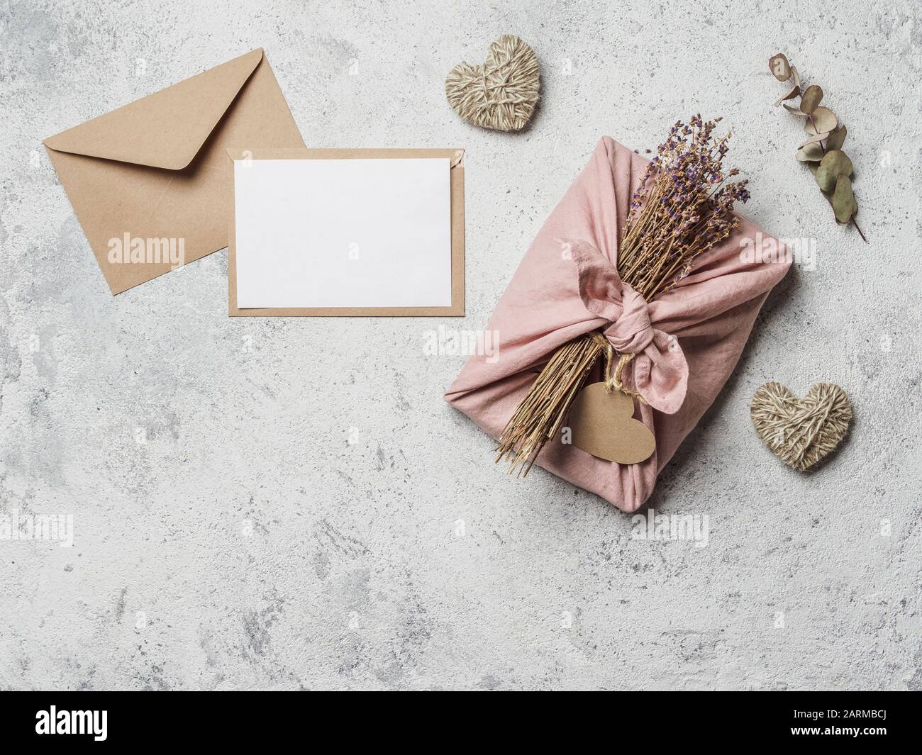 Valentinstag ohne Verschwendung und verspotten. Umweltfreundliche Geschenktuchverpackung im Furoshiki-Stil, Briefumschlag, leeres Geschenk oder Grußkarte, Platz für Kopien Stockfoto