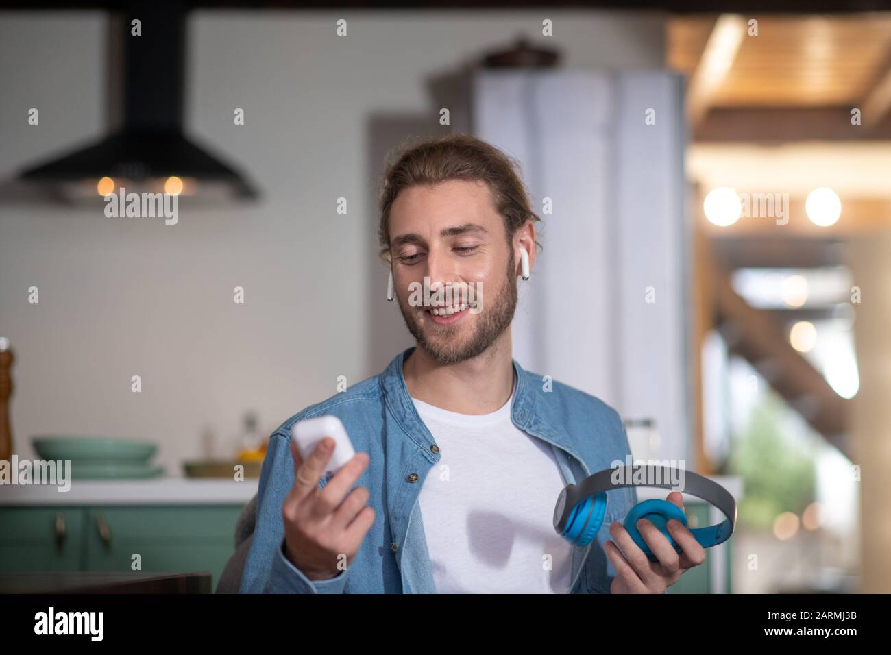 Junger Mann, der verschiedene Arten von Ohrhörern testet Stockfoto