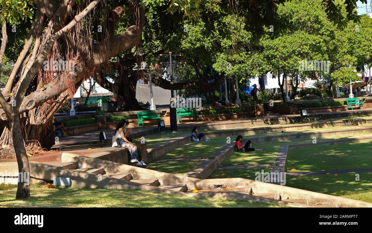 Bangkok, Thailand-28. Januar 2020: Gruppe von Menschen, die im Schatten des Baumes im öffentlichen Park von Santi Chai Prakan in der Nähe des Chao Phraya Flusses sitzen und sich entspannen Stockfoto