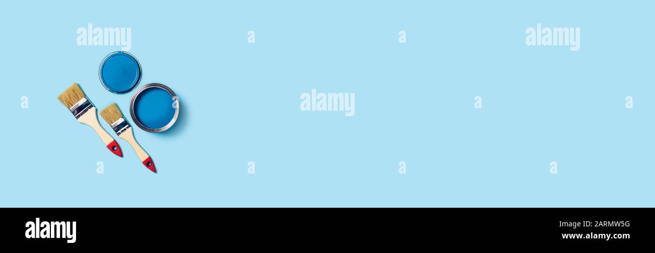 Foto für Wohnungsreparaturen. Blauer Hintergrund mit Farbe und zwei Holzquasten. Stockfoto