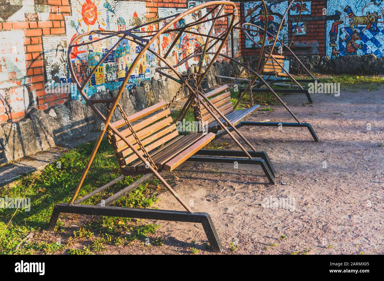 Alte Holzbank im sowjetischen Retro-Stil schwenkt im Sommer im Park in der Nähe der Mosaikwand Stockfoto