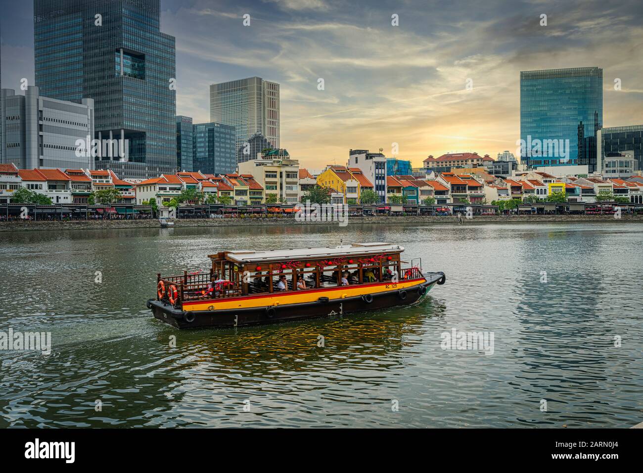Singapur. Januar 2020. Ein Boot auf dem Fluss Singapur mit typischen Ladenhäusern im Hintergrund Stockfoto
