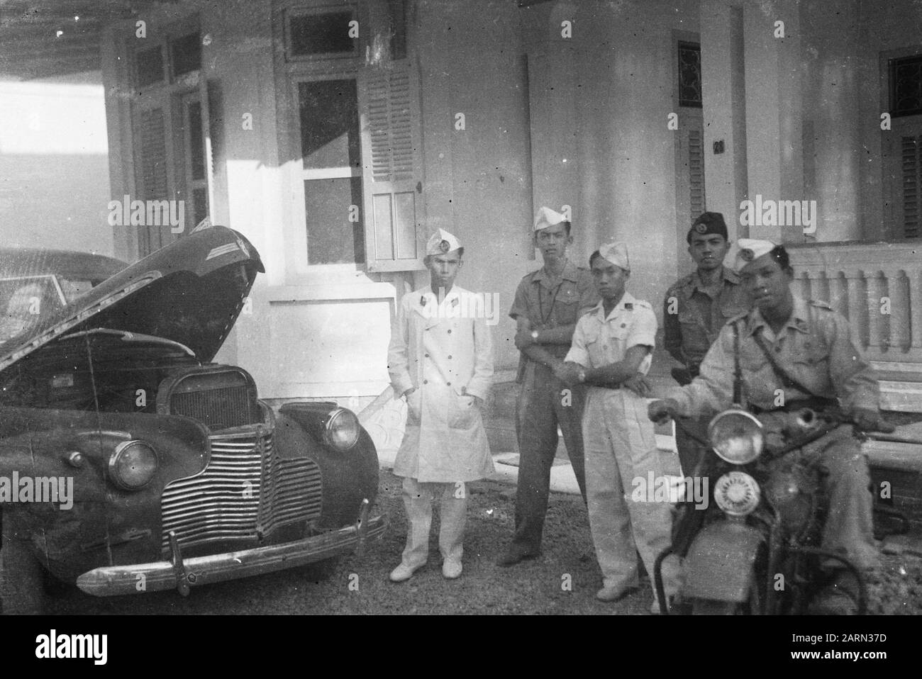 Die drei Offiziere von Batavia, Fünf Offiziere des T.R.I., stellen sich in der Nähe eines Autos mit offener Motorhaube auf. Ein Sit on a Motorcycle Annotation: Fot NEFIS (Foto aufgenommen?) Datum: 1947 Ort: Batavia, Indonesien, Jakarta, Niederländisch-Ostindien Stockfoto