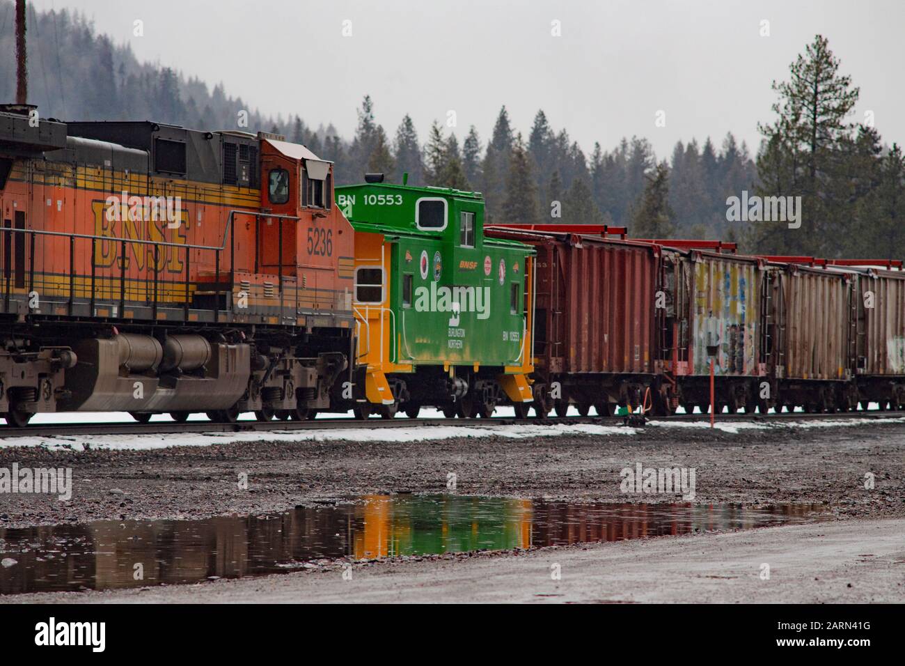 Eine Burlington Northern BNSF Railroad caboose und eine Linie von Kastenwagen hinter einer BNSF-Diesellokomotive, auf den Gleisen in der Stadt Troy, Montana. Stockfoto