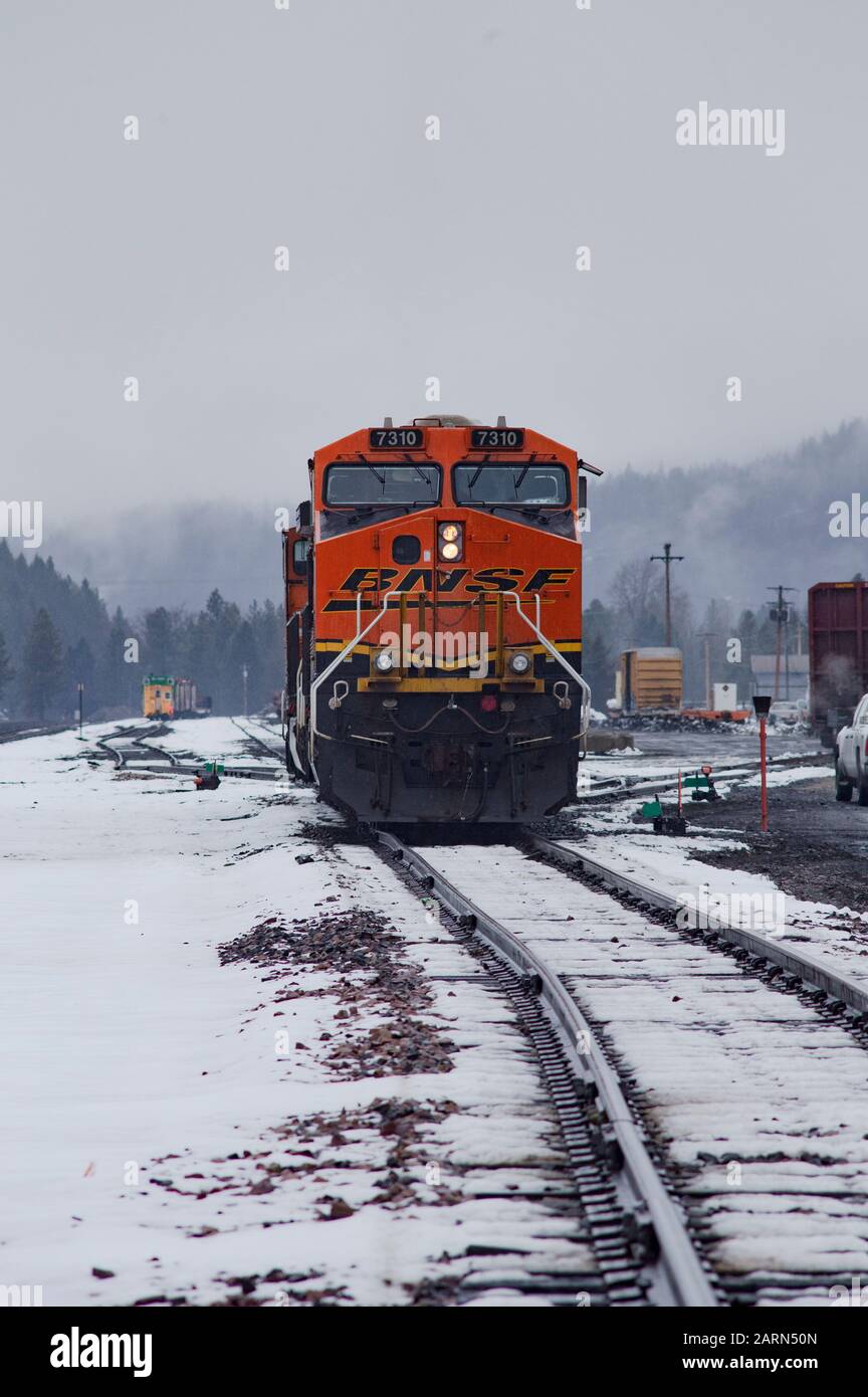 Eine schwarze, gelbe und orangefarbene BNSF-Lok, die im Leerlauf auf den Gleisen in der Stadt Troy, Montana, fuhr. Burlington Northern and Santa Fe Railway wurde in gebildet Stockfoto
