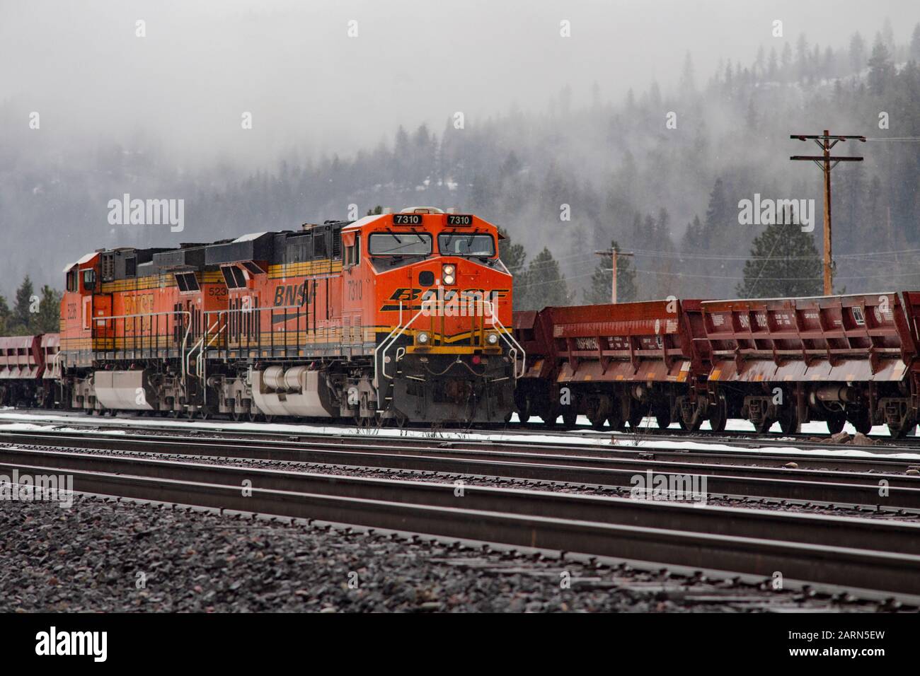 Eine schwarze, gelbe und orangefarbene BNSF-Lok, die im Leerlauf auf den Gleisen in der Stadt Troy, Montana, fuhr. Burlington Northern and Santa Fe Railway wurde in gebildet Stockfoto