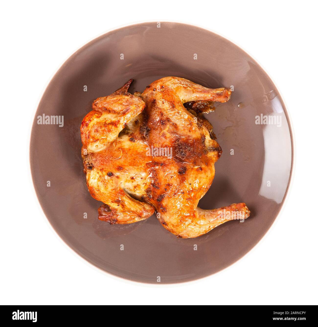 Draufsicht des gebratenen ganzen abgeflachten Hühnchens auf brauner Platte isoliert auf weißem Grund Stockfoto