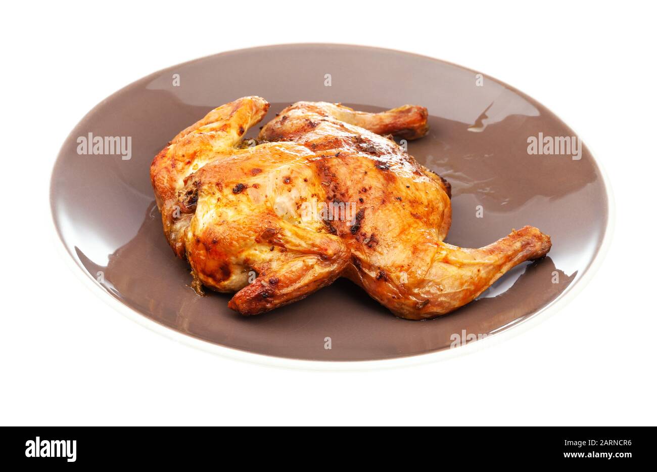 Gebratenes komplettes abgeflachtes Huhn auf brauner Platte isoliert auf weißem Grund Stockfoto