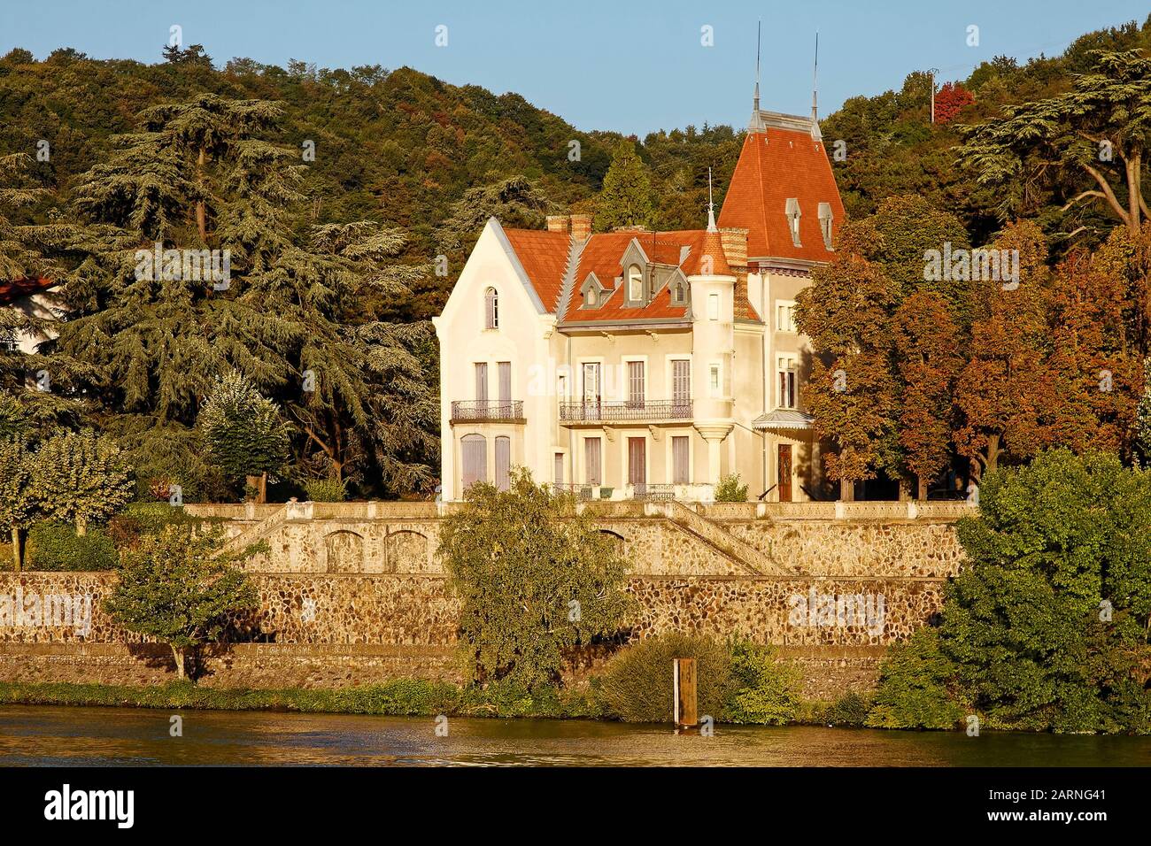 Attraktives altes Haus, entlang der Rhone, hohes rotes Dach, hohe Fenster, Balkone, Wasserwand, Wasser, Bäume, goldenes Licht, Vienne, Frankreich, summe Stockfoto