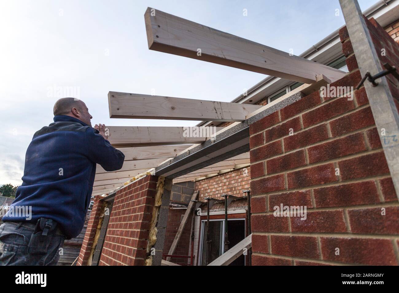 Ein Gebäudeanbau in Stockton an Tees, England, Großbritannien, zeigt einen Bauunternehmer, der auf den Dachtrusseln festhält, wenn sie in Position gebracht werden Stockfoto
