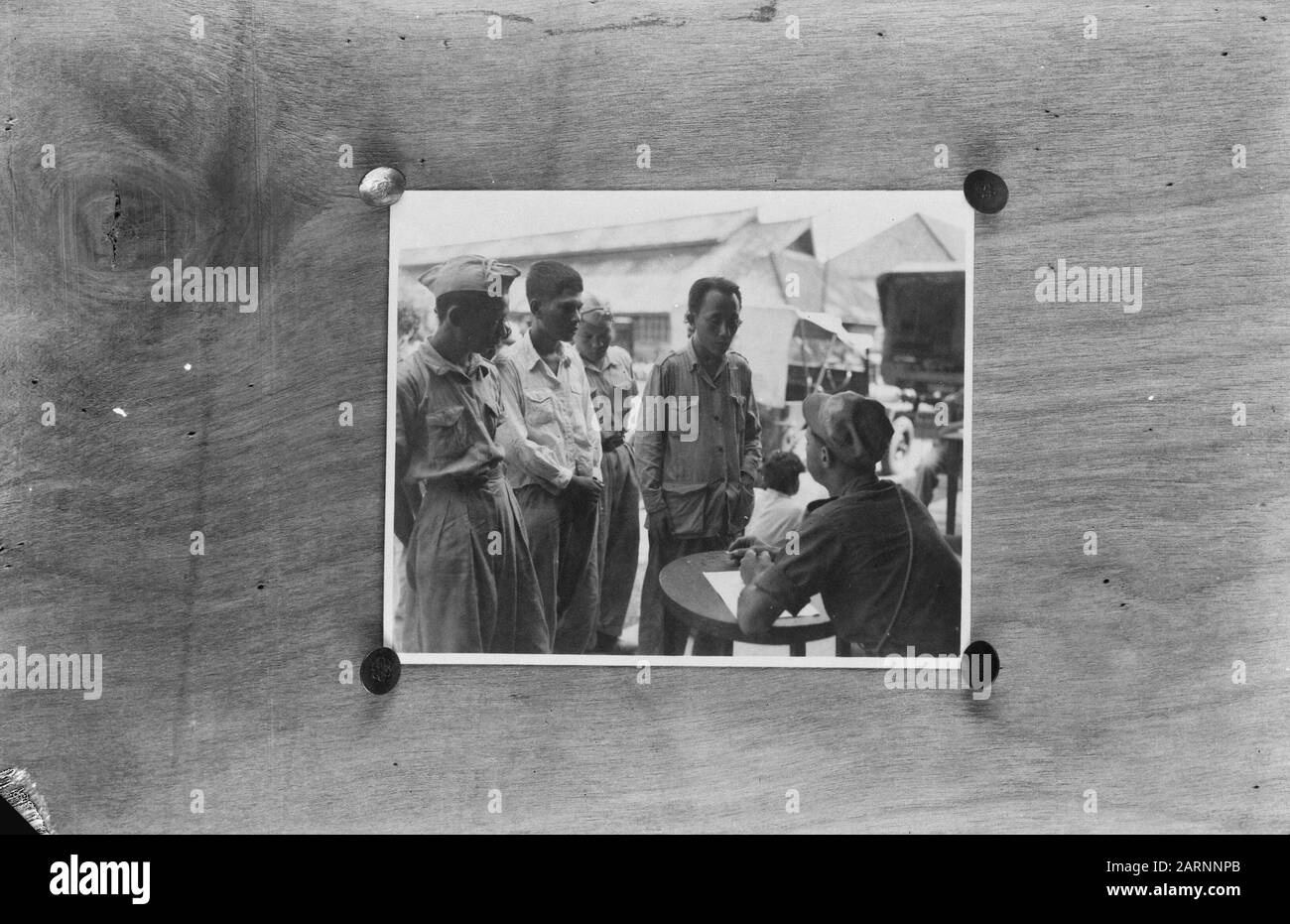 [Vier indonesische Soldaten stehen vor einem anderen indonesischen Soldaten, der an einem Tisch sitzt und aufschreibt] Datum: 1947/01/01 Ort: Indonesien, Niederländische Ostindien Stockfoto