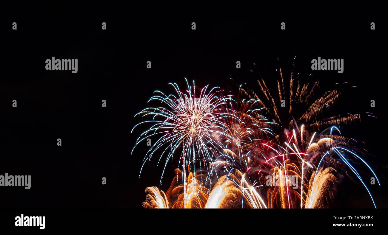 Feuerwerk mit Goldbrunnen mit roten Höhepunkten unter weißem Starburst-Feuerwerk, das am vierten Juli in Minnesota gegen einen schwarzen Himmel fotografiert wurde Stockfoto