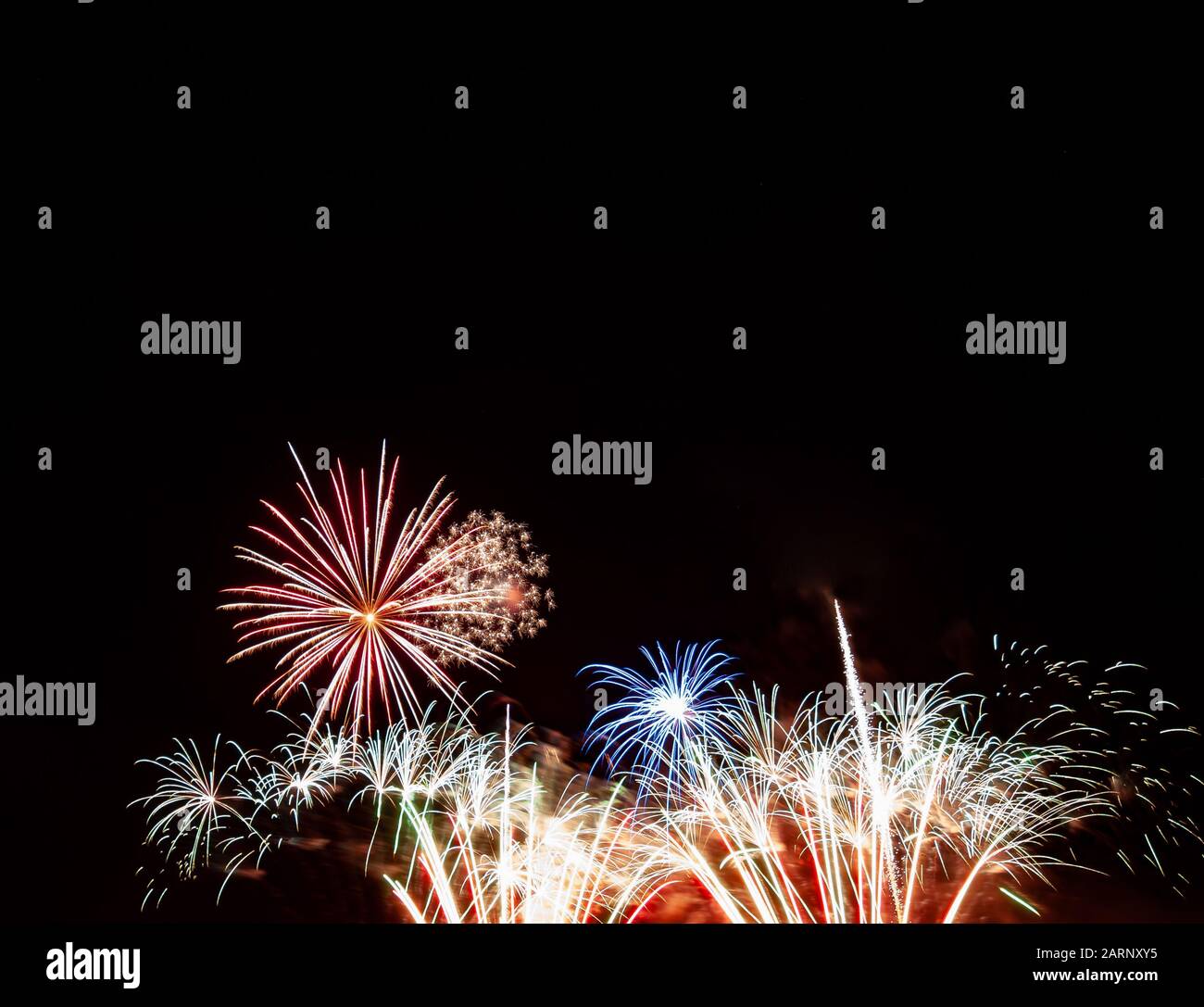 Rotes Starburst, blaues Starburst über goldenem und weißem Feuerwerk, das am vierten Juli in Minnesota gegen einen schwarzen Himmel fotografiert wurde Stockfoto