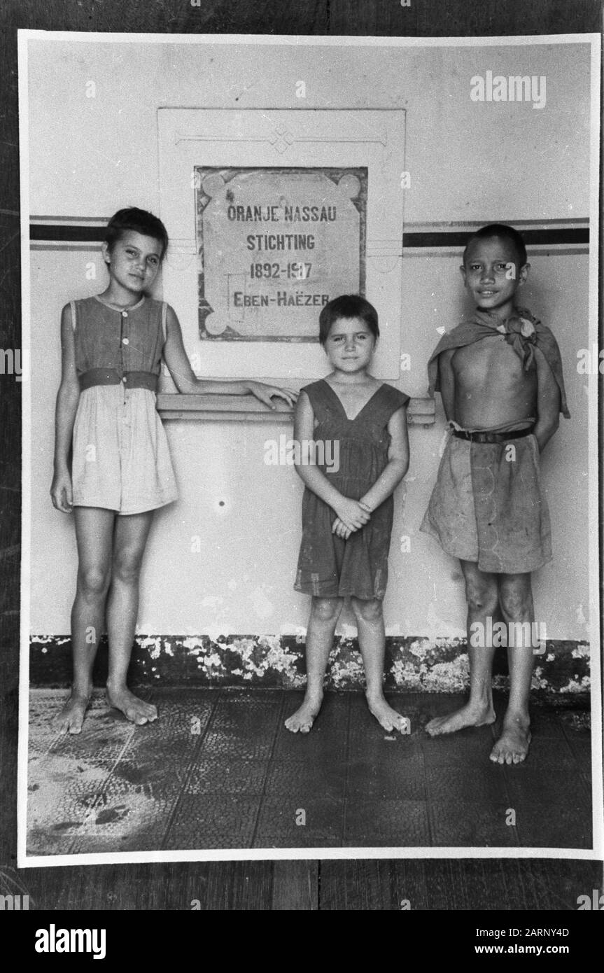 Magelang In Magelang wurde am Eingang der niederländischen Truppen vom bekannten Bildungsinstitut Pa van der Seur. De Orange Nassaus in Richtung Magelang eine Reihe von Kindern gefunden. Die Kinder waren in schlechter Verfassung. Einige der Störe vor dem Eingang ihrer zerstörten Kirche Anmerkung: Repronegativ. [Drei Kinder, davon zwei Niederländer für eine Tafel mit der Aufschrift Oranje Nassau-Stich 1892-1917 Eben-Haëzer] Datum: 22. Dezember 1948 Ort: Indonesien, Java, Magelang, Nederlands-Indies Stockfoto