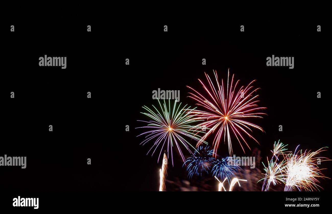 Ein grünes, rotes, blaues und weißes Starburst-Feuerwerk, das am vierten Juli in Minnesota gegen einen schwarzen Himmel fotografiert wurde Stockfoto
