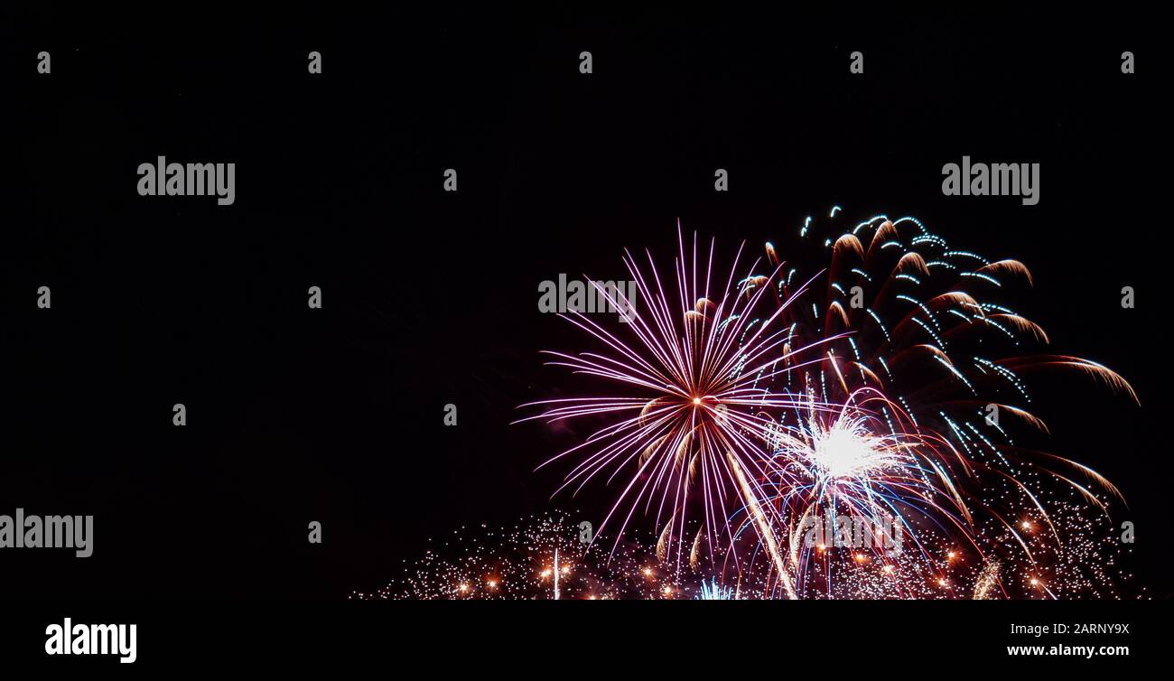 Weißes Starburst-Feuerwerk mit mehreren kleinen Goldgräben und roten Höhepunkten, die am vierten Juli in Minnesota gegen einen schwarzen Himmel fotografiert wurden Stockfoto