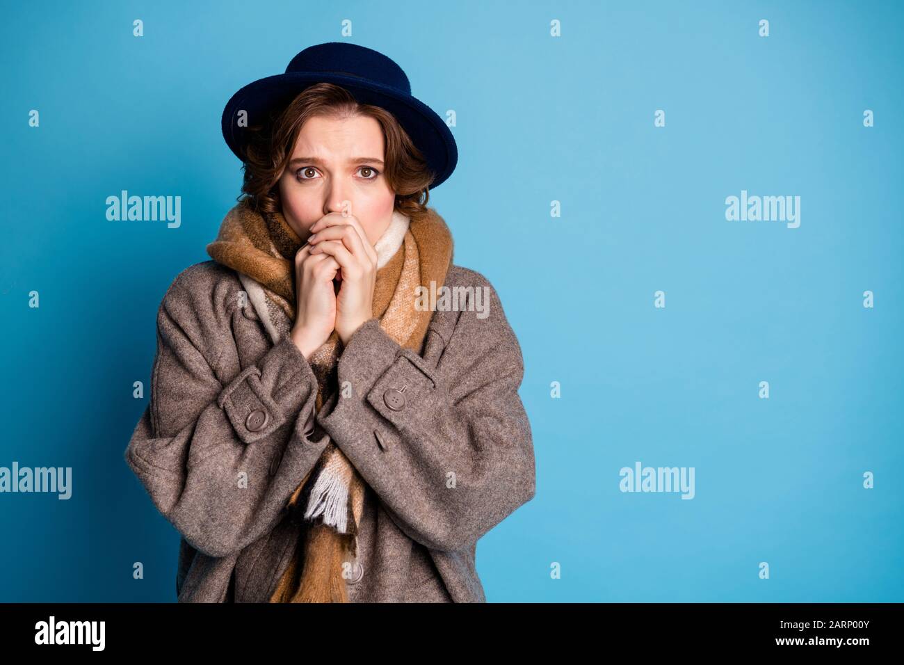 Foto der Reisenden Dame hat Probleme mit kaltem Wetter unerwarteter frostiger Tag, der Mund warm zu den Armen weht, modisch legere lange graue Mantel Schal Kappe Stockfoto