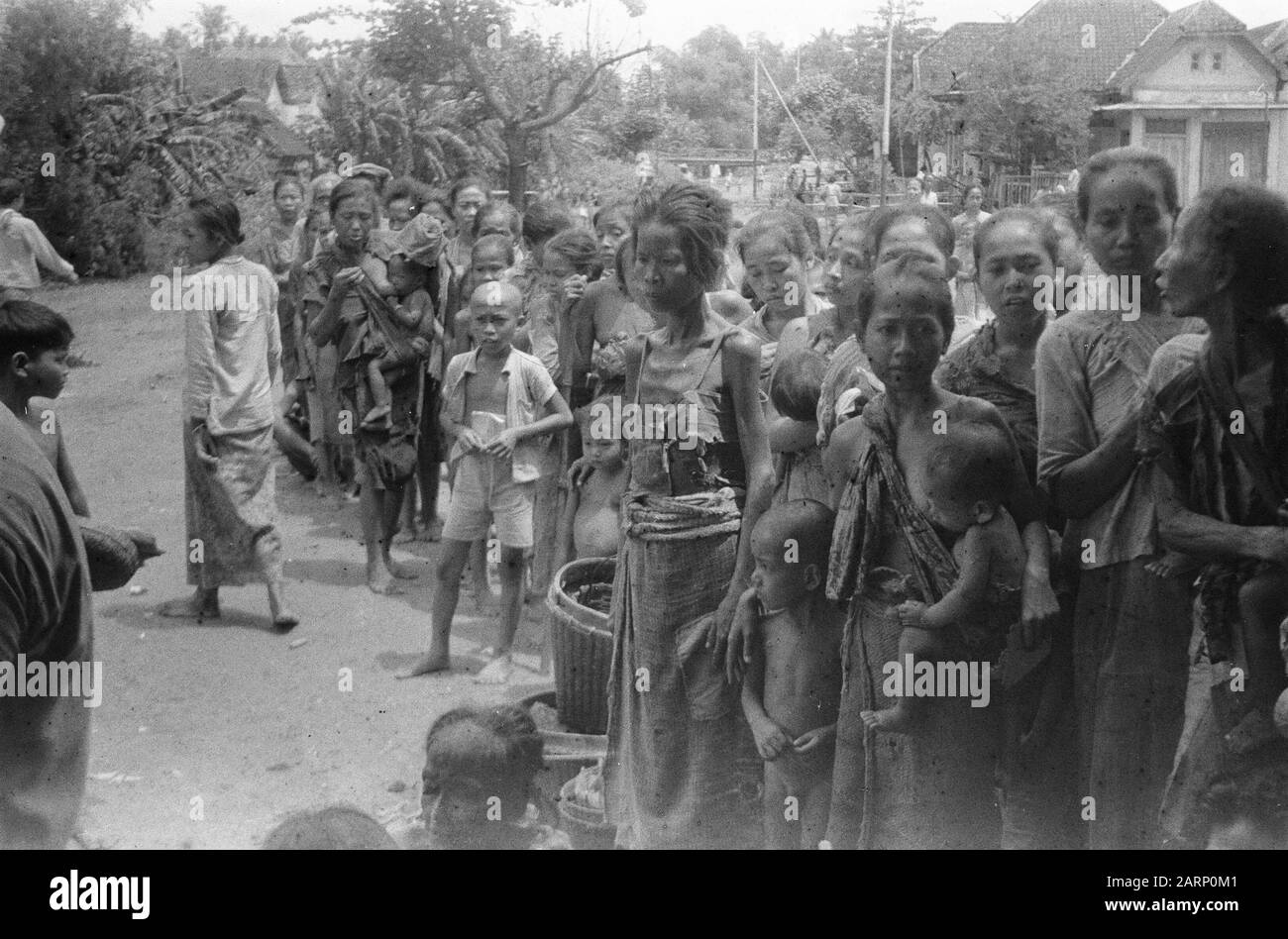 Djombangs, Surabaya Aus Djombangs fährt täglich ein Lastwagen mit Evakuierten nach Modjokerto und Surabaya. Diese Personen flüchteten während der ersten Polizeiaktion ins Landesinnere, die in der Regel von der TNI erzwungen wurde. Sie kehren nun gerne in ihre Kernstädte zurück, was auch durch die Pflege des Roten Kreuzes und der sozialen Angelegenheiten geschieht. Die arme Bevölkerung brauchte Lebensmittel und Kleidung. Hier stehen sie in Reihe und warten auf die Dinge bis zum Datum: Februar 1949 Ort: Indonesien, Java, Niederländische Ostindien Stockfoto