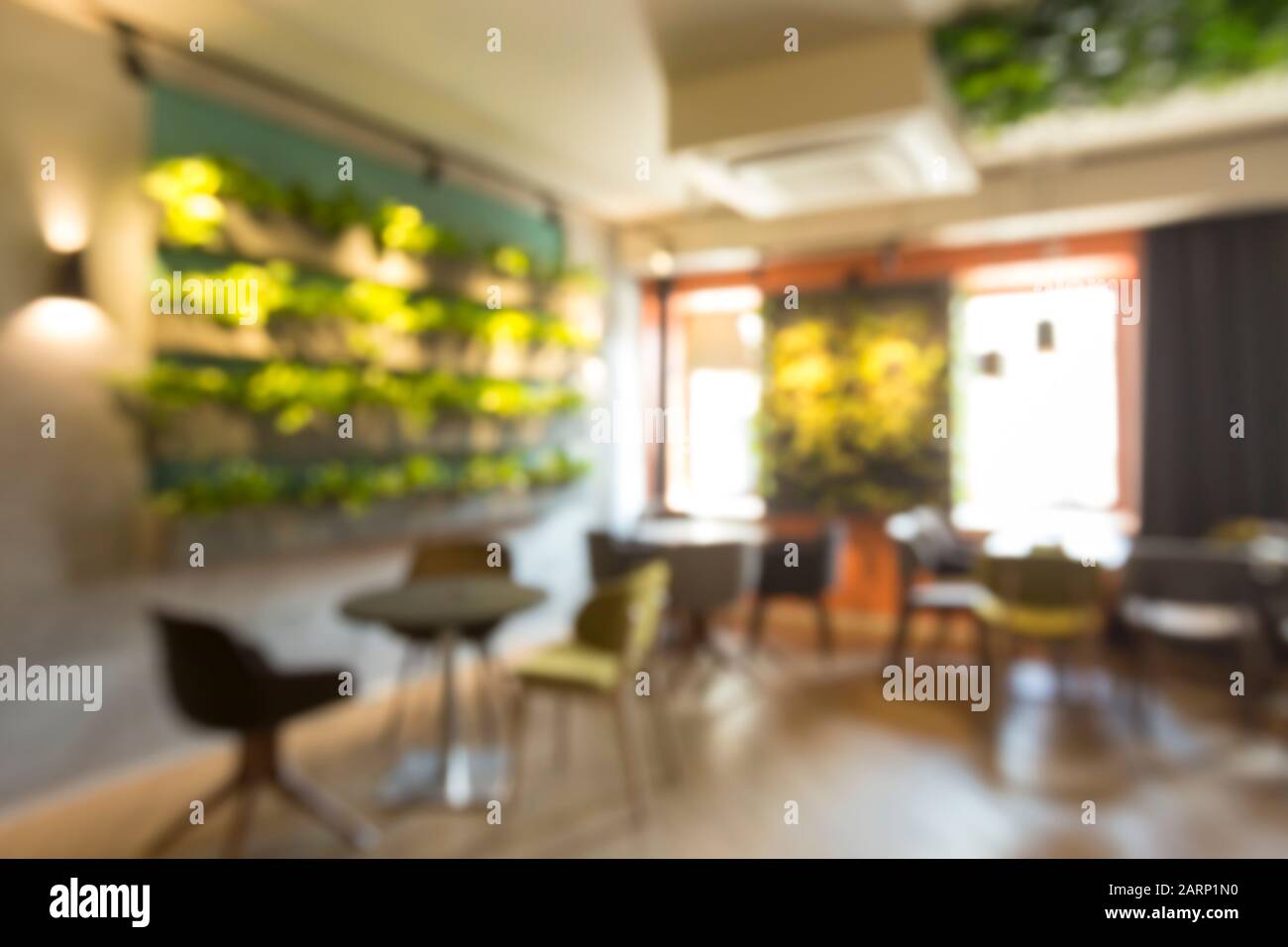 Verschwommenes grünes Café-Interieur mit lebenden Wänden Pflanzen Stockfoto