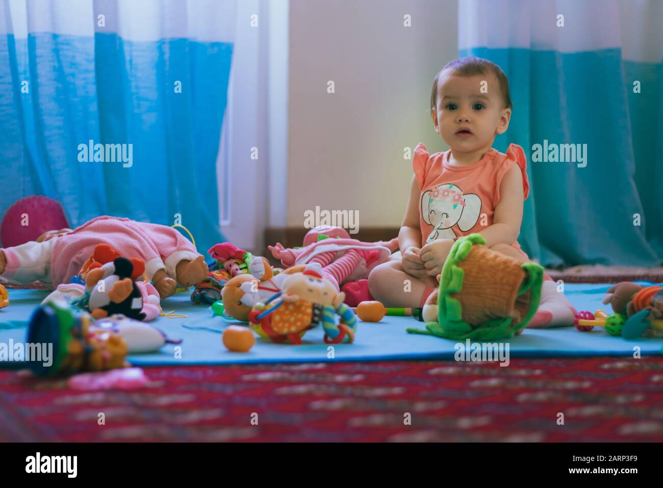 Ein süßes kleines Mädchen, das zu Hause auf dem Boden Spielzeug spielt. Stockfoto