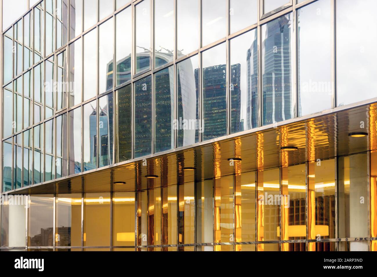 Wolkenkratzer spiegelten sich in der Glasfassade des modernen Gebäudes in London, Großbritannien, wider Stockfoto