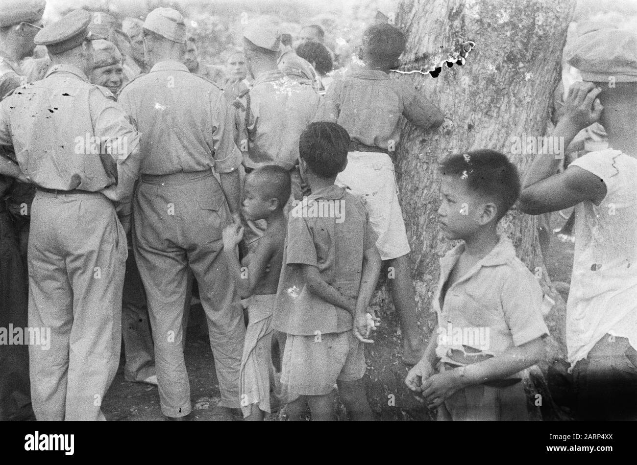 Indonesische Kinder stehen mit einer Gruppe von Soldaten, die miteinander sprechen Datum: 1947/01/01 Ort: Indonesien, Niederländische Ostindien Stockfoto