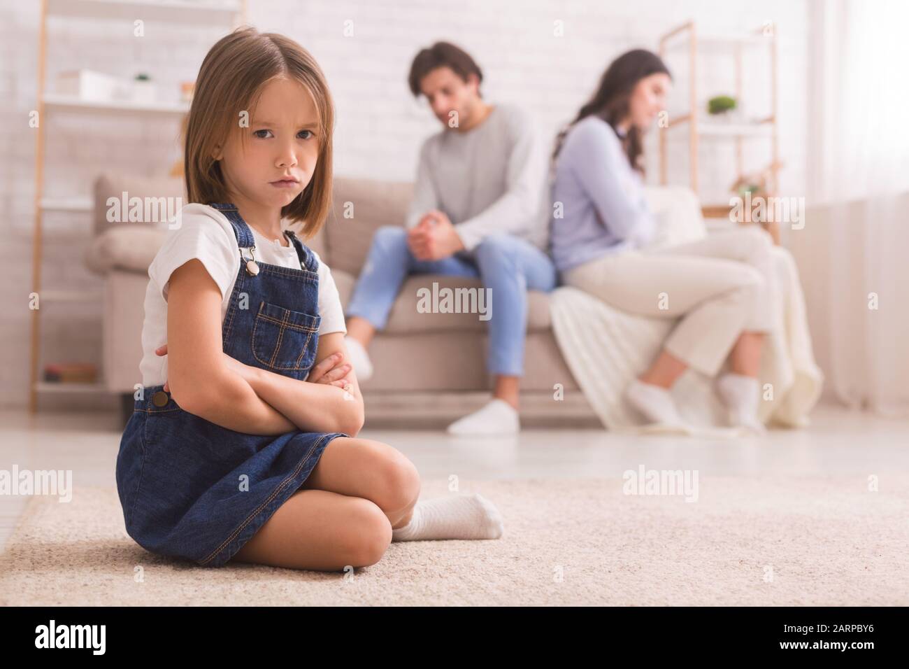 Kleines Mädchen, das nach ihrem Streit getrennt von Mutter und Vater sitzt Stockfoto