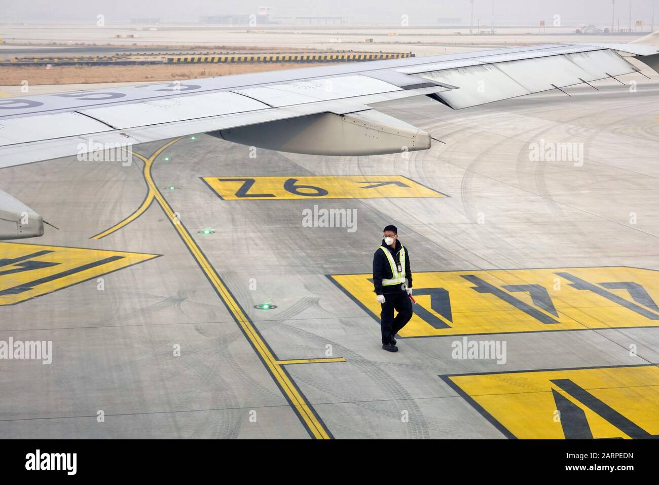 Ein chinesisches Bodenbesatzungsmitglied, das eine Gesichtsmaske zur Vorbeugung des neuen Coronavirus trägt, und eine Lungenentzündung, läuft an einem Flugzeug in der Beijing Daxing Internationa vorbei Stockfoto