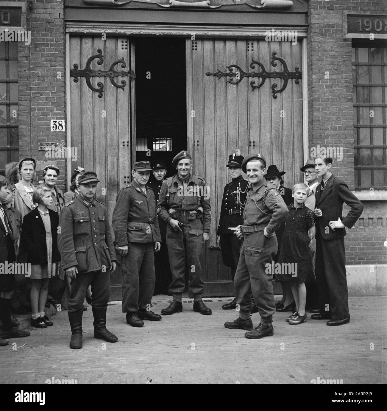 Kriegsverbrecher Zwei Mitglieder der Brigade Prinzessin Irene mit links zwei gefangenen deutschen Soldaten vor dem Haus der Untersuchungshaft Anmerkung: Soldaten der Wehrmacht und Luftwaffe Datum: 1945 Ort: Amsterdam , Noord-Holland Schlüsselwörter: Befreiung, Häuser der Haft, Kriegsgefangene, Militär Stockfoto