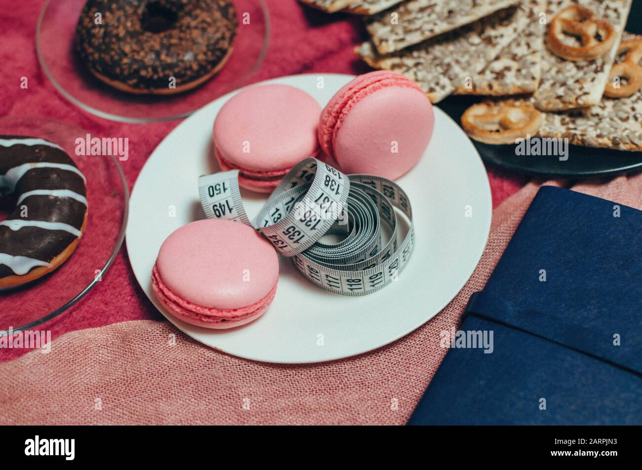 Maßband auf weißem Teller in der Nähe von Süßigkeiten und Gebäck messen Stockfoto